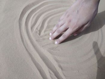 High angle view of woman hand on sand