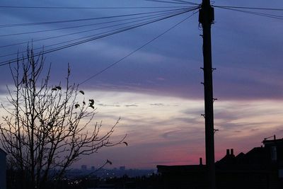 Low angle view of power lines against cloudy sky