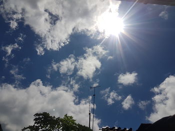 Low angle view of sun shining through clouds