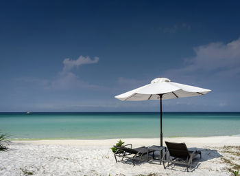 Deck chairs on beach against sky