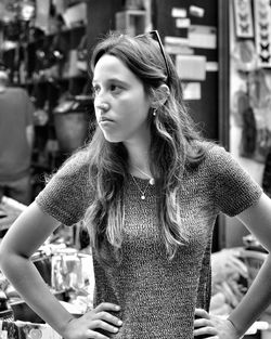 Young woman with hand on hip standing against store