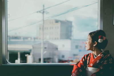 Portrait of young woman looking through window