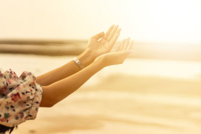 Young woman praying hands at sunset