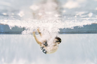Full length of shirtless boy swimming underwater in pool