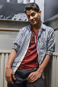 Portrait of young man standing against wall