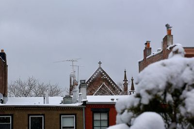 Church by snow covered buildings against sky