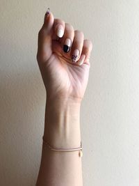 Cropped image of hand wearing bracelet against wall