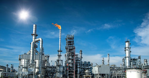 Low angle view of illuminated factory against blue sky