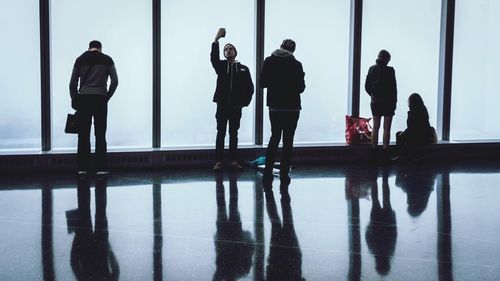 Silhouette people standing in water against sky