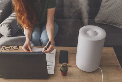 Midsection of woman using laptop on table at home