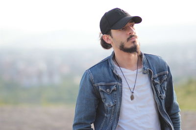 Thoughtful man wearing cap while standing outdoors