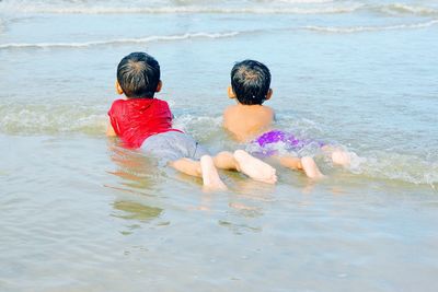 Rear view of boys lying down at beach