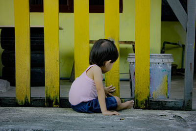 Side view of boy sitting on yellow umbrella