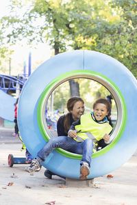 Happy teacher playing with boy in tube at playground