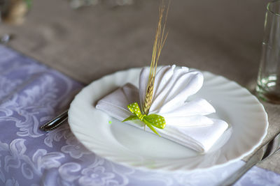 High angle view of folded napkin with ear of wheat in plate on table