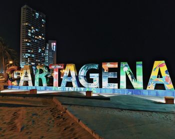 Graffiti on illuminated building against sky at night