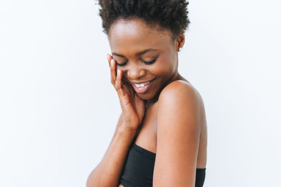 Portrait of smiling beautiful young african american woman in black top isolated on white background