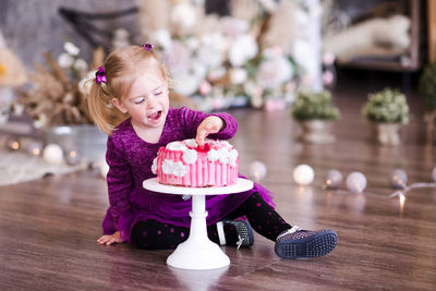 Cute girl touching cake at home