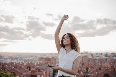 Young woman standing on mobile phone against cityscape