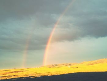 Rainbow over landscape against sky