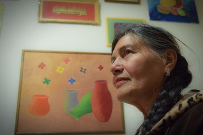 Portrait of woman looking away against wall at home