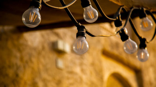 Low angle view of illuminated light bulbs hanging from ceiling