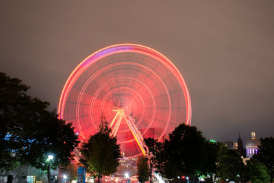 Illuminated ferris wheel against sky at night