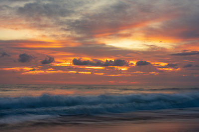 Scenic view of sea against dramatic sky during sunset