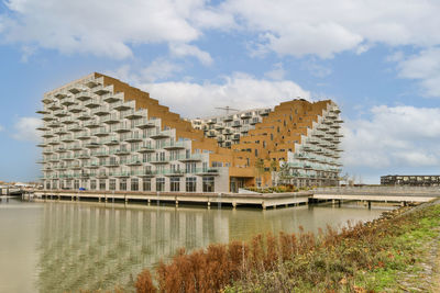 Buildings by river against sky