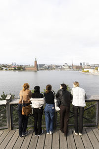 Rear view of female tourists looking at sea while standing near railing on vacation