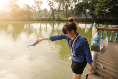 Woman pouring food in lake