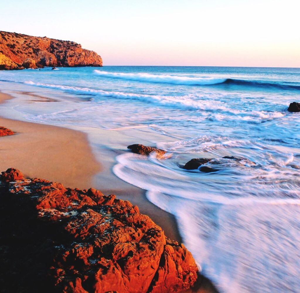 sea, horizon over water, beauty in nature, nature, water, scenics, wave, tranquil scene, rock - object, beach, tranquility, clear sky, sky, sunset, outdoors, motion, no people, day