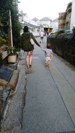 Rear view of woman walking on footpath in city