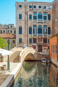 Bridge over canal by buildings in city