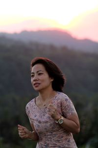 Woman looking away against mountains during sunset