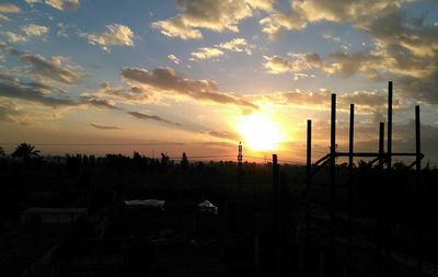 Silhouette of factory against sky during sunset