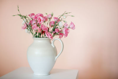 Close-up of pink flower vase on table against wall