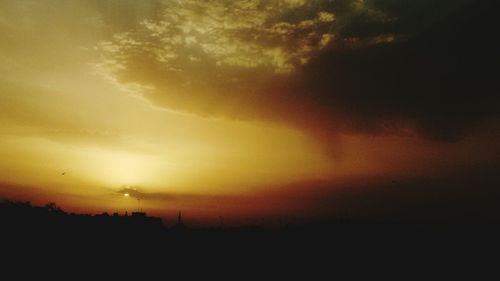 Silhouette landscape against dramatic sky during sunset