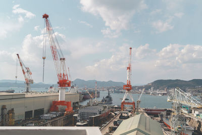 Cranes at commercial dock against sky