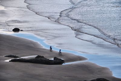 High angle view of people riding bicycles on shore at beach