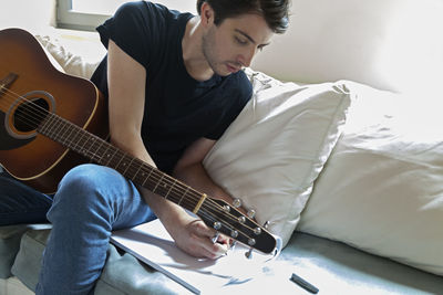 Young musician writing songs on an acoustic guitar