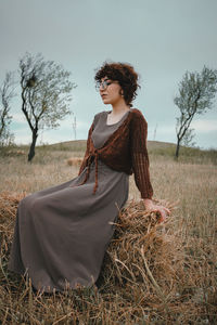 Young woman sitting on the hay bale