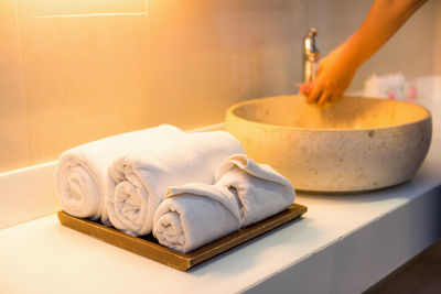 Close-up of person washing hands in sink by towels on table