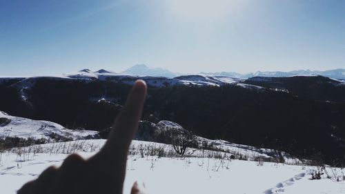 Cropped hand against snowcapped mountain
