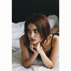 Thoughtful young woman lying on bed at home