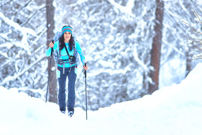 Young woman practicing ski touring during a snowfall in the woods