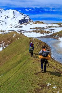 Rear view of people walking on mountain during winter