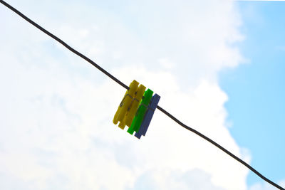 Low angle view of clothespins on rope against sky