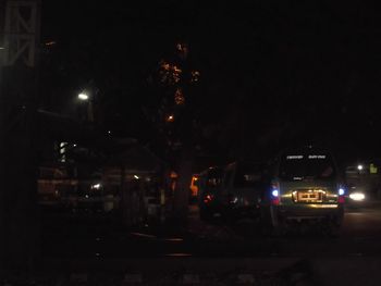 Illuminated cars against sky at night