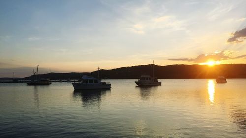 Boats in sea against sky during sunset